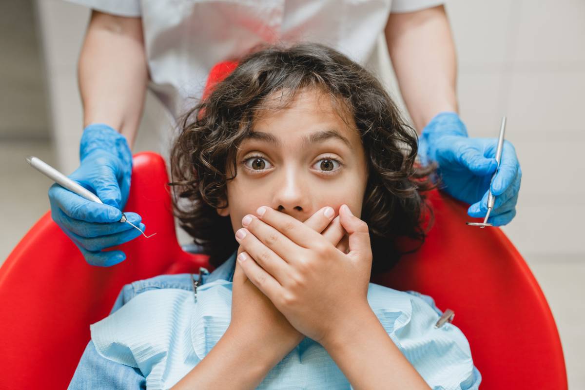Boy covering his mouth, afraid of dentist.